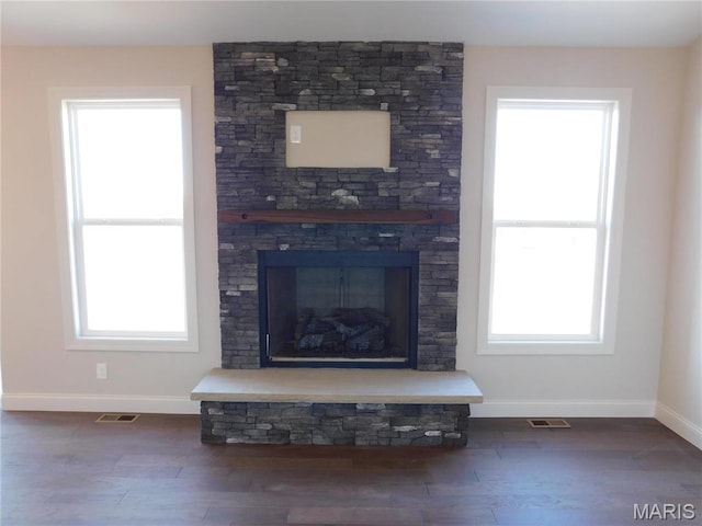 detailed view of baseboards, wood finished floors, and a fireplace