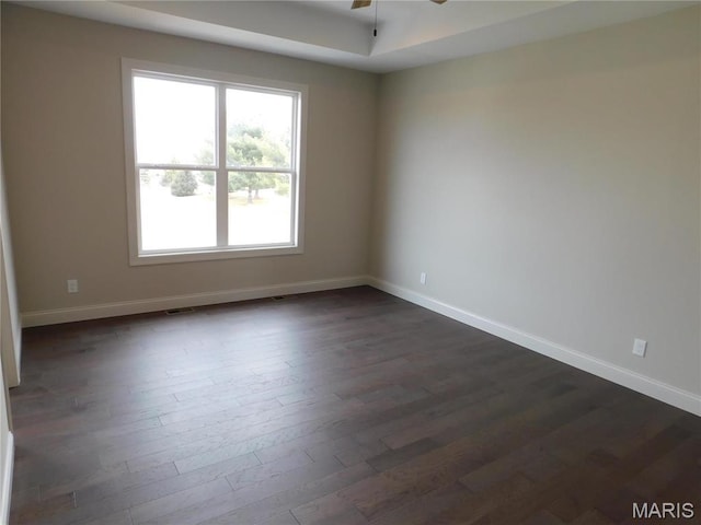 unfurnished room with dark wood-style floors, healthy amount of natural light, baseboards, and a ceiling fan