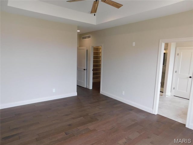 unfurnished room featuring a ceiling fan, baseboards, and dark wood-type flooring