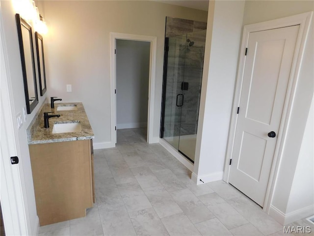 full bath featuring baseboards, a stall shower, and double vanity