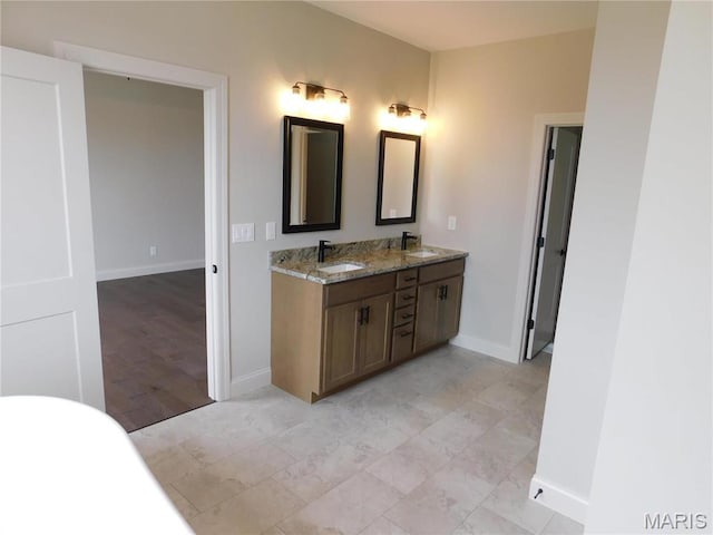 full bathroom with double vanity and baseboards