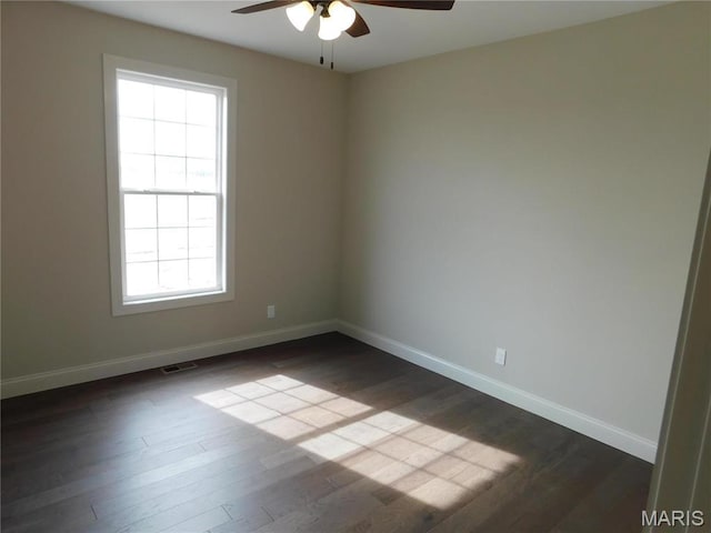 empty room featuring ceiling fan, dark wood-type flooring, plenty of natural light, and baseboards