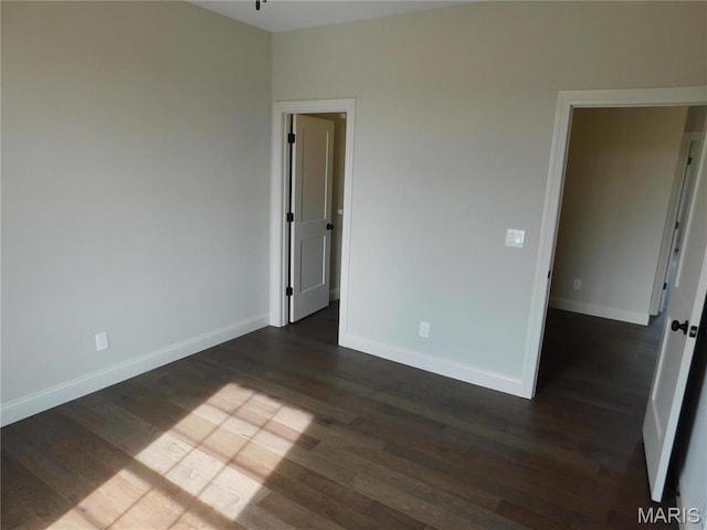 spare room with dark wood-type flooring and baseboards