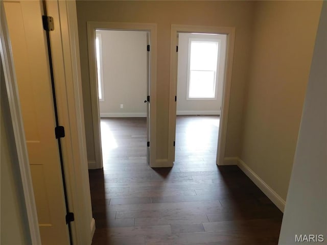 corridor with dark wood-style flooring and baseboards