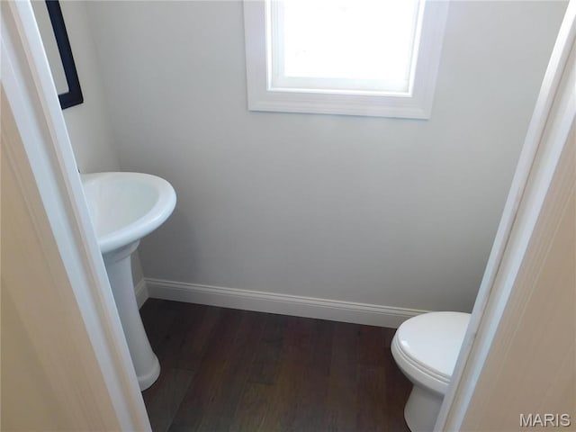 bathroom featuring baseboards, wood finished floors, and toilet