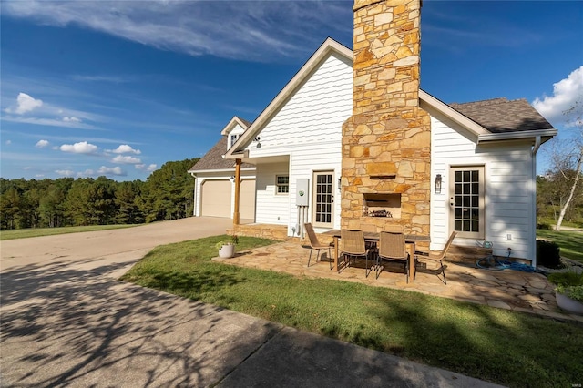 view of front of house featuring an outdoor stone fireplace, an attached garage, driveway, and a shingled roof