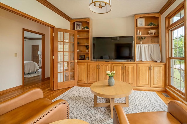 living area featuring light wood-style flooring, healthy amount of natural light, ornamental molding, a chandelier, and baseboards