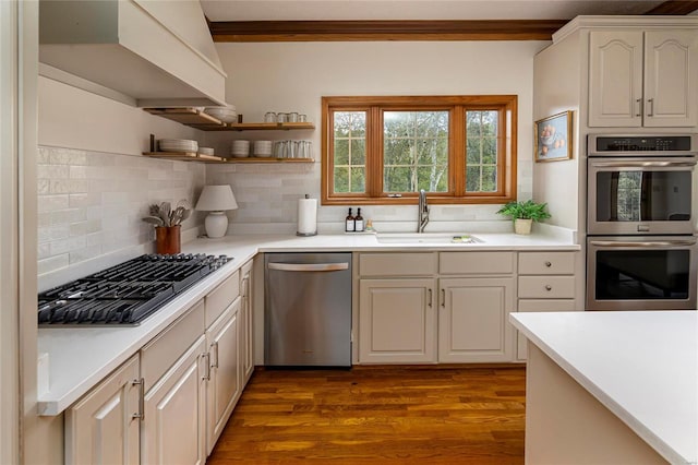 kitchen with stainless steel appliances, a sink, backsplash, dark wood finished floors, and crown molding