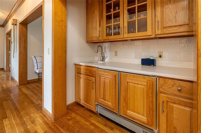 bar with dark wood-style flooring, a sink, tasteful backsplash, baseboards, and ornamental molding