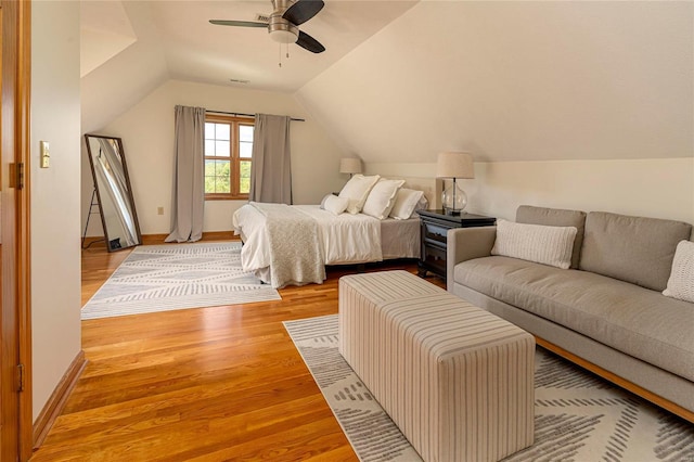 bedroom with light wood-style flooring, vaulted ceiling, a ceiling fan, and baseboards
