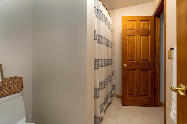 bathroom with tile patterned floors, toilet, a shower with shower curtain, and baseboards