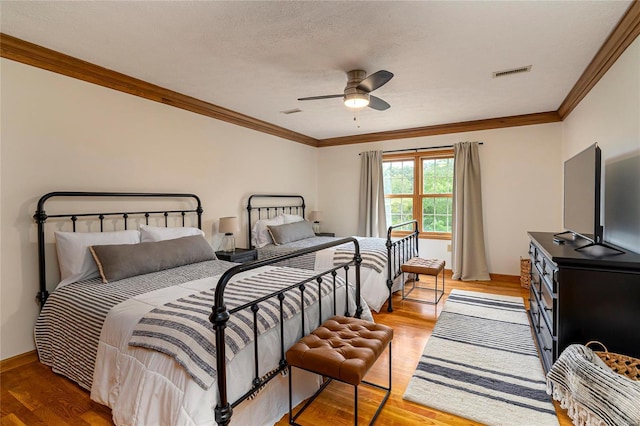 bedroom with crown molding, light wood-style flooring, a ceiling fan, baseboards, and a textured ceiling