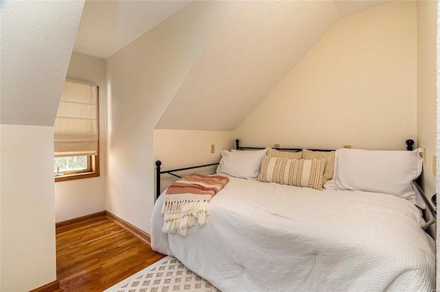 bedroom with lofted ceiling, wood finished floors, and baseboards