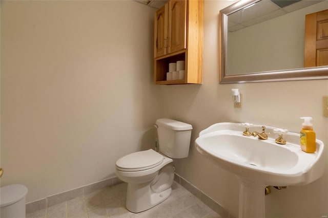 half bath featuring toilet, baseboards, and tile patterned floors
