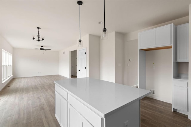 258 Noser Dr, Florissant, MO 63031 - kitchen with dark wood-style floors, a kitchen island, ceiling fan, hanging light fixtures, and white cabinets
