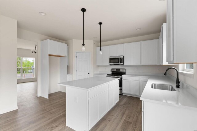 258 Noser Dr, Florissant, MO 63031 - kitchen featuring appliances with stainless steel finishes, a sink, a kitchen island, light wood-style floors, and white cabinetry