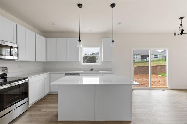 258 Noser Dr, Florissant, MO 63031 - kitchen featuring stainless steel appliances, a sink, light wood-style floors, light countertops, and a kitchen island