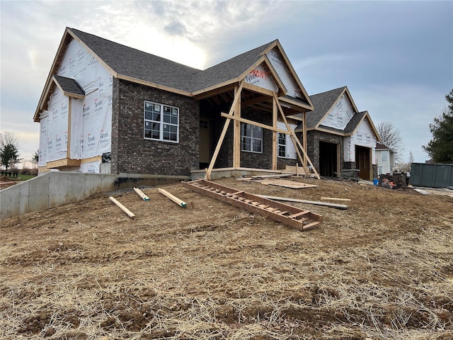 back of house featuring brick siding and roof with shingles