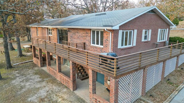 24950 State Rd A, Richland, MO 65556 - rear view of house featuring brick siding, a deck, roof with shingles, and a patio