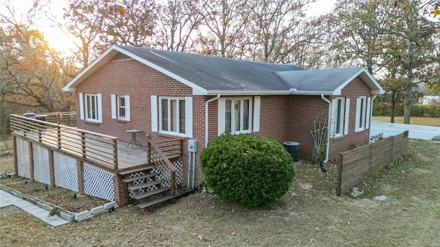 24950 State Rd A, Richland, MO 65556 - view of home's exterior with a deck, brick siding, roof with shingles, and central AC