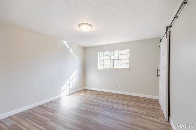 2637 Forest View St, Poplar Bluff, MO 63901 - spare room featuring a barn door, a textured ceiling, wood finished floors, and baseboards
