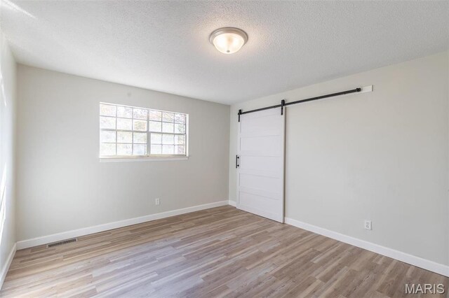 2637 Forest View St, Poplar Bluff, MO 63901 - unfurnished bedroom with a barn door, wood finished floors, a textured ceiling, and baseboards