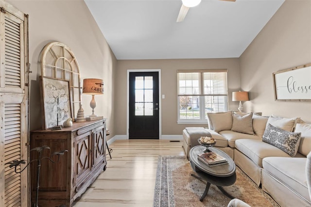 living area with light wood-style floors, lofted ceiling, a ceiling fan, and baseboards