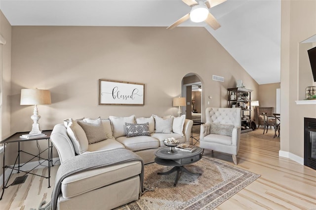 living room featuring a ceiling fan, wood finished floors, arched walkways, lofted ceiling, and baseboards