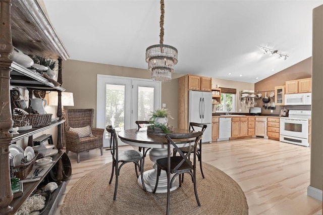 dining room featuring a chandelier, lofted ceiling, light wood finished floors, and rail lighting
