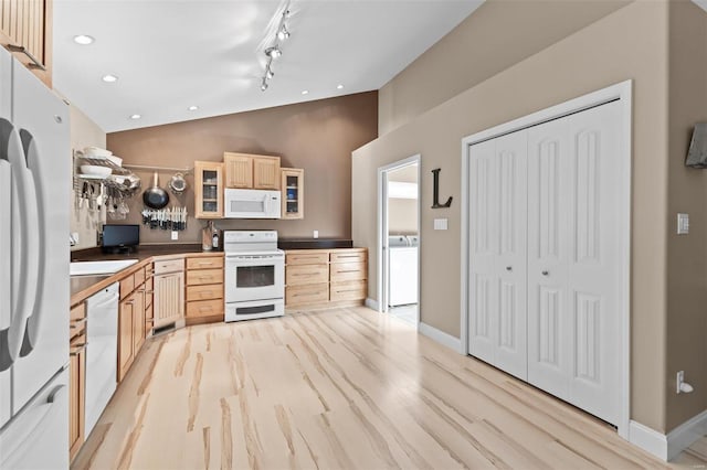 kitchen with white appliances, light brown cabinetry, washer / dryer, glass insert cabinets, and high vaulted ceiling