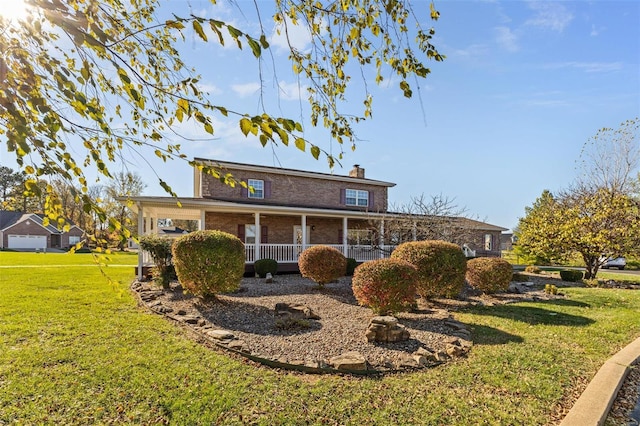 back of property with a yard, a chimney, brick siding, and covered porch