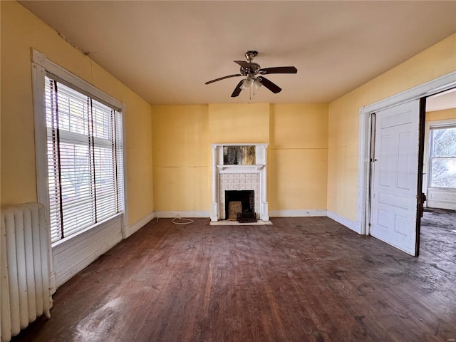 5168 Vernon Ave, Saint Louis, MO 63113 - unfurnished living room with radiator heating unit, dark wood finished floors, ceiling fan, a brick fireplace, and baseboards
