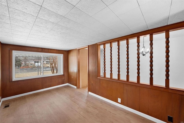empty room with wood finished floors, baseboards, and wood walls