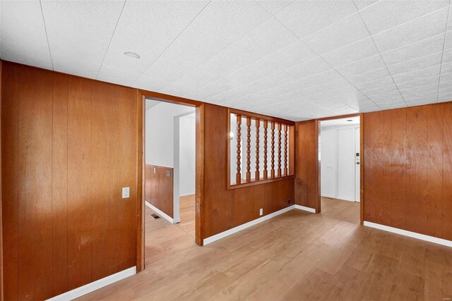 unfurnished room with wood finished floors, wood walls, and baseboards