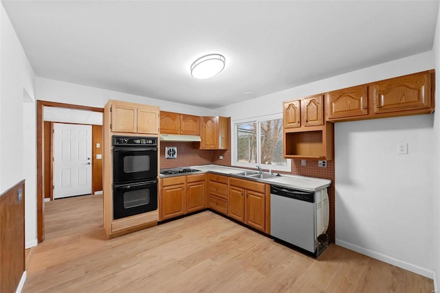kitchen featuring dishwasher, a sink, backsplash, and light wood finished floors