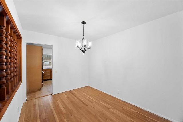 unfurnished dining area with a chandelier, light wood finished floors, and baseboards