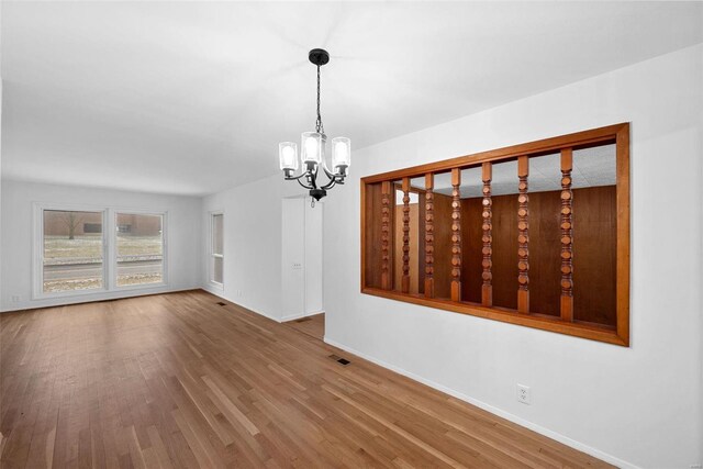 unfurnished dining area featuring a chandelier, wood finished floors, and baseboards