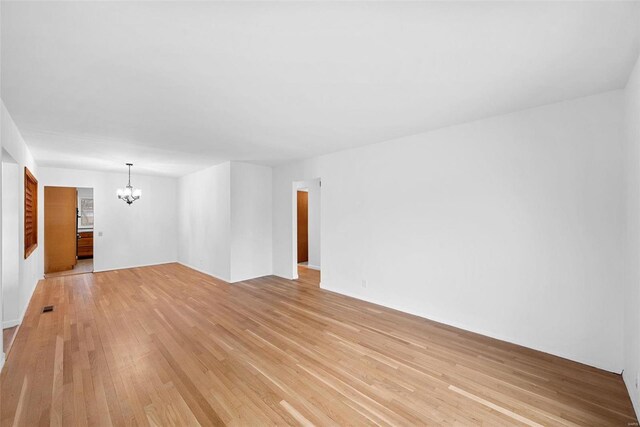 unfurnished living room with a chandelier and light wood-style floors