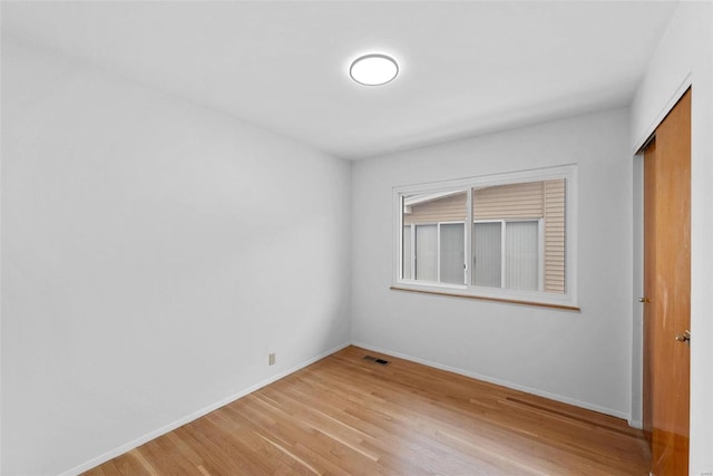 empty room featuring light wood finished floors and baseboards
