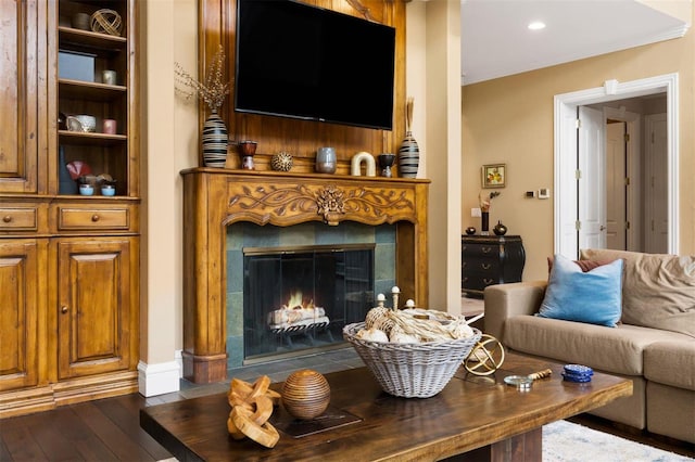living area with a fireplace, dark wood-style floors, and crown molding