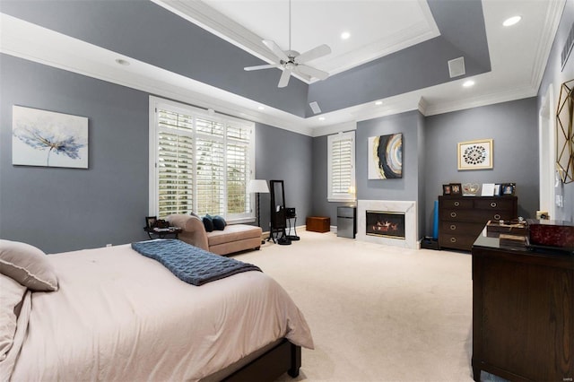 bedroom featuring carpet flooring, a raised ceiling, recessed lighting, ornamental molding, and a glass covered fireplace
