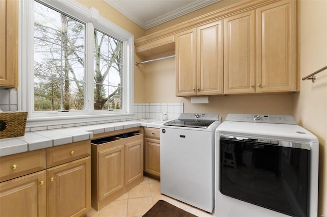 laundry room featuring cabinet space, separate washer and dryer, healthy amount of natural light, ornamental molding, and light tile patterned floors