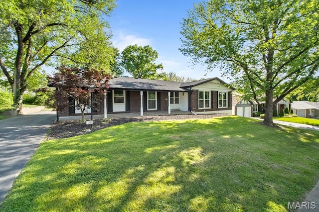 single story home featuring asphalt driveway, brick siding, a front lawn, and covered porch
