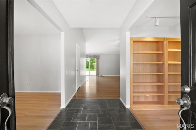 foyer featuring rail lighting, baseboards, and wood finished floors