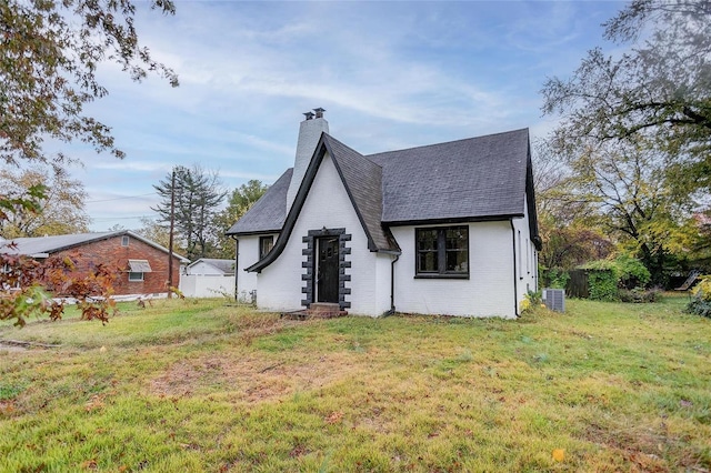 view of front of home featuring a chimney, brick siding, roof with shingles, and central air condition unit