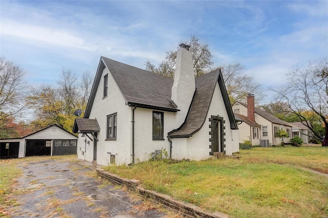 view of side of property with brick siding, a lawn, a chimney, an outdoor structure, and central AC