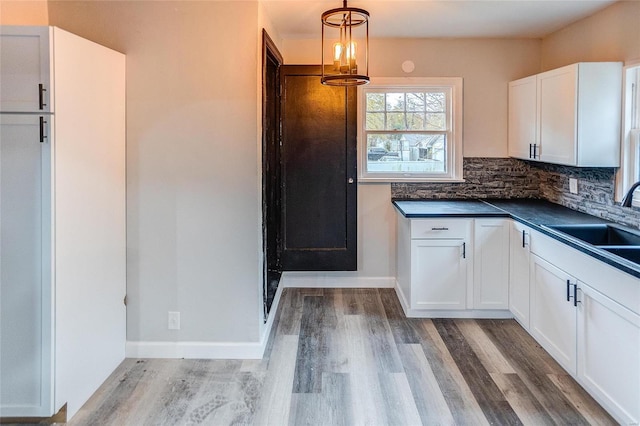 kitchen featuring dark countertops, light wood-style flooring, a sink, and white cabinetry