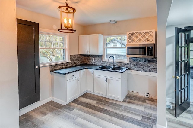 kitchen with stainless steel microwave, a sink, light wood finished floors, and white cabinets