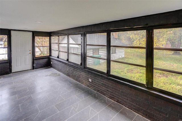 unfurnished sunroom with brick wall