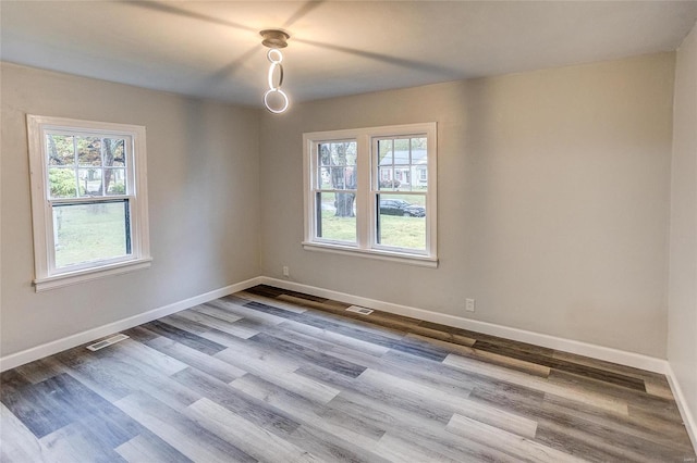 empty room with healthy amount of natural light, baseboards, and wood finished floors